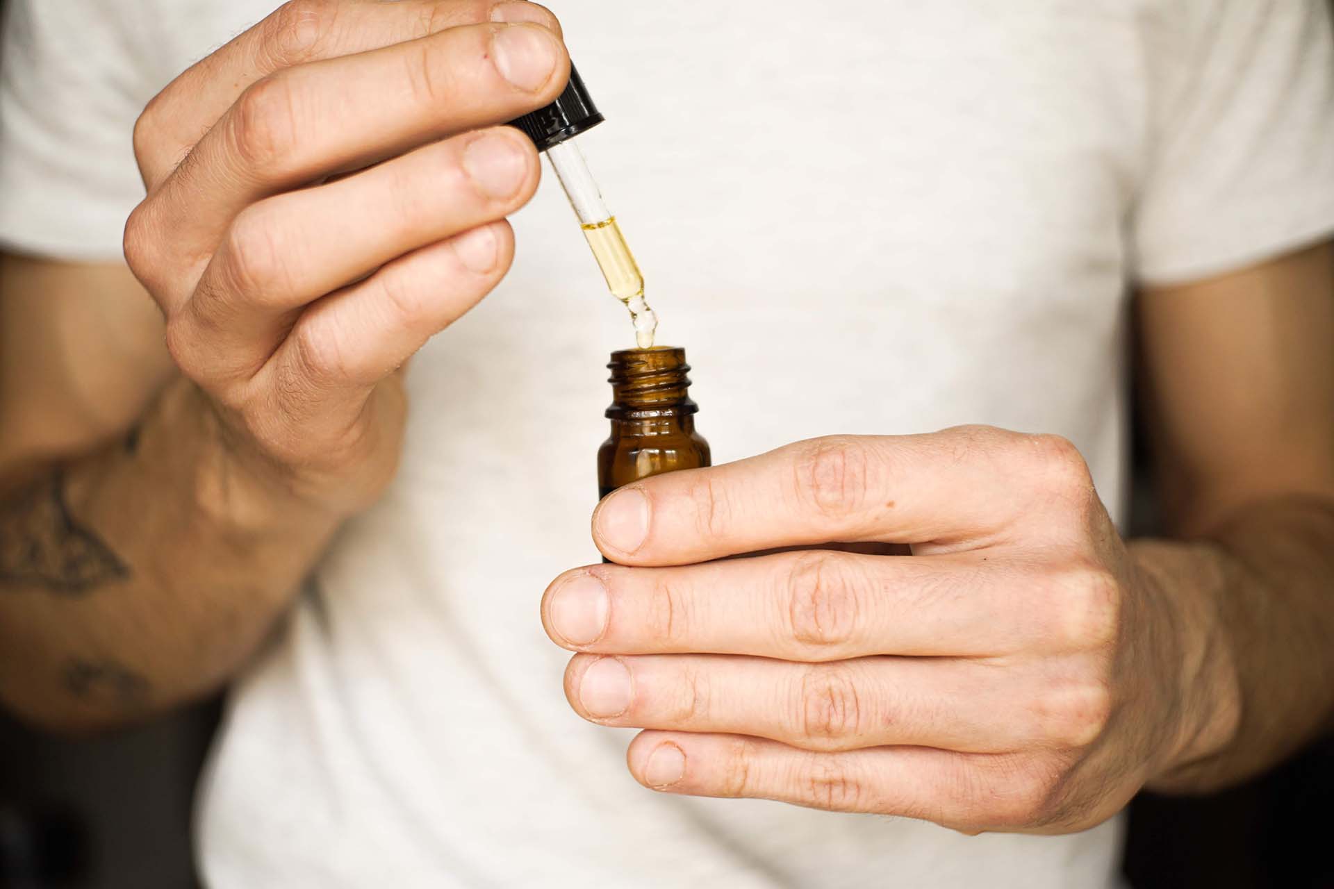 Person holding opened bottle of CBD liquid (image)