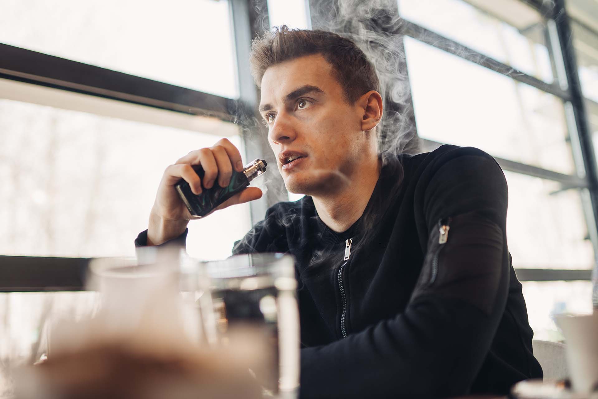 Man holding a vape device, vaping in a public place (Image)