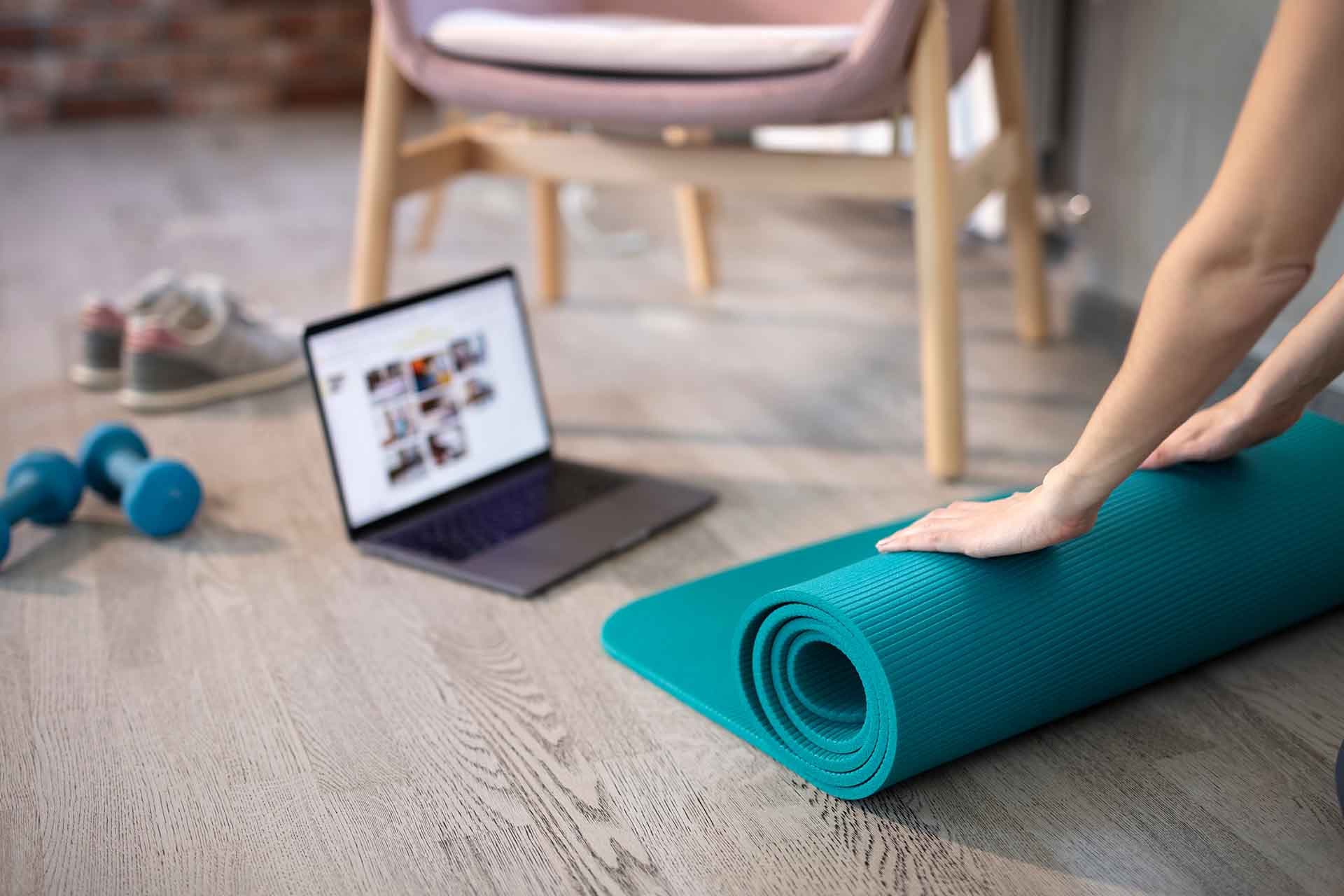 person beginning a workout with yoga mat in living room (image)